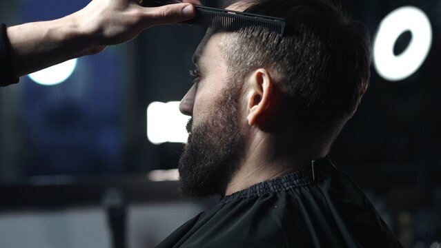 Skilled barber grooming client's hair with precision, working inside contemporary barbershop setting, preparing stylish haircut