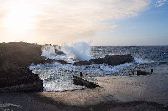 Waves crashing on volcanic rocks at sunset in linosa, pelagie islands, sicily