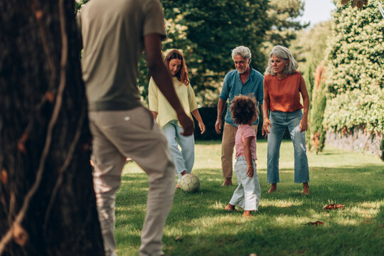 Multigenerational family playing soccer in the park