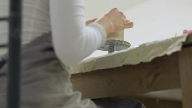 A close-up of the hands of a woman who sculpts a mug from clay at a pottery master class. The process of creating a mug from clay. Creative hobby.