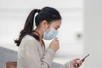 Young woman in a mask expressing concern while using her phone in a polluted urban environment.