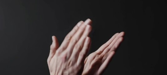 Hands clapping in rhythm against black background: movement and gesture study