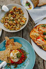 A vibrant Mediterranean meal at a seaside restaurant in Fethiye, Türkiye. Featuring fresh burrata, crispy zucchini chips, artisanal bread, and smoked salmon pizza on a rustic wooden table