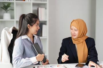 Diverse female finance professionals discussing strategies in a modern office setting.