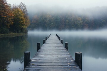 Foggy Wooden Pier Extending Into Calm Lake Surrounded By Autumn Forest And Misty Atmosphere