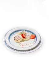 beautiful cheesecakes on a white plate with sour cream and strawberries sprinkled with powdered sugar