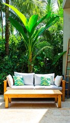 A tropical setting featuring a wooden couch situated on a stone floor surrounded by lush greenery.