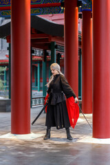 A warrior girl in a Chinese costume practices wushu kung fu with weapons in an open area. National...
