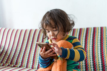 Close up of baby girl looking at mobile phone display checking internet and social media. Concept...