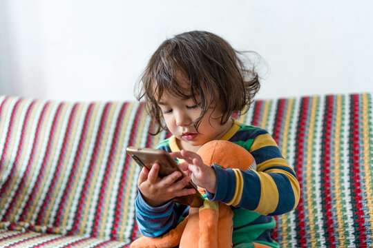 Close up of baby girl looking at mobile phone display checking internet and social media. Concept of screen addiction and social media addiction in children