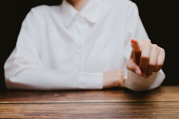 Close-Up of Person Pointing Finger from Table on Dark Background