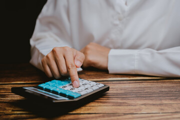 Close-Up of a Hand Using a Calculator on a Wooden Table Surface
