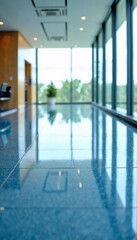 Fototapeta premium A modern office space with polished blue floors and large windows offering a view of trees outside.
