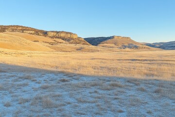 Serene Landscape of Frosty Meadow and Rocky Hills at Dawn