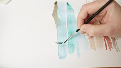 An artist skillfully applies watercolor to paper, blending vibrant hues to create an abstract design. The warm and inviting workspace enhances the creative process.