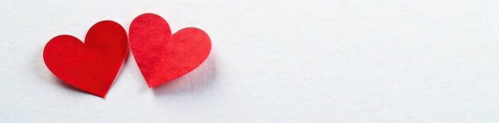 Fototapeta premium Two red heart stickers on white paper, slightly overlapping , graphic, decoration, minimal