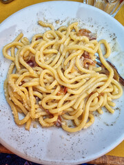 Top view of Spaghetti alla Carbonara, typical italian recipe of pasta with guanciale, egg ad pecorino romano cheese served in a traditional italian restaurant in Trastevere, Rome, Italy.