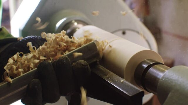 In a workshop, an artisan skillfully operates a lathe to shape a wooden spindle. The attention to detail showcases the craftsmanship involved in creating handcrafted items.