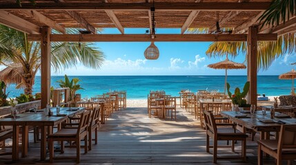 Outdoor beach restaurant with wooden tables and chairs overlooking the turquoise ocean
