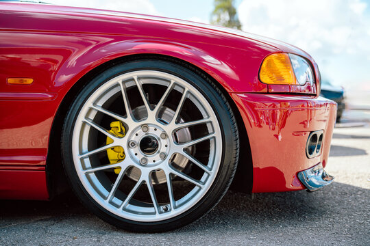 Close-Up of a Red Car's Alloy Wheel with Yellow Brake Calipers in Sunlight