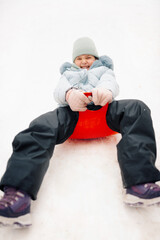 Happy girl sliding downhill on red sled in winter wonderland