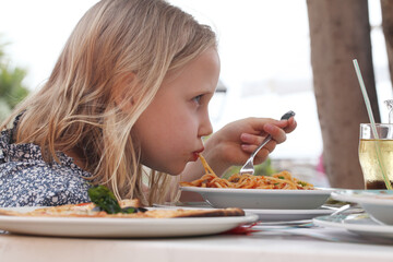 Cute child girl eating Italian spaghetti