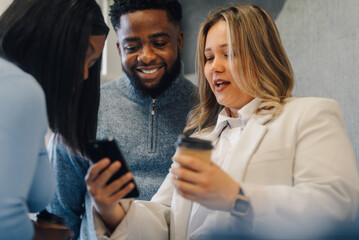 Businesswoman showing smartphone content to colleagues during coffee break