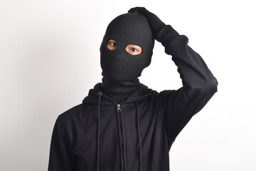 Thief wearing black jacket and mask grabbing his head, isolated on white background. Robbery and...