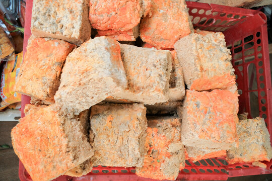 Fresh raw oncom displayed at a traditional food stall (warung), showcasing its textured surface and vibrant orange hue. A fermented soybean product used in Indonesian cuisine