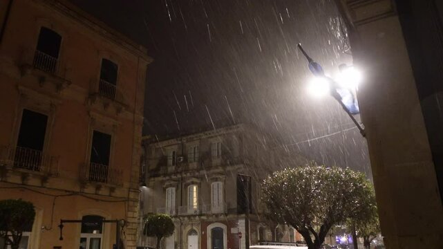 Massive rain during heavy storm 'Helios', evening shot with light, a damaged flag and historic buildings. Extreme weather conditions in Siracusa, Italy Europe
