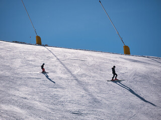 Skiers practicing their sport on the descent of a ski slope in a resort on a sunny winter day....