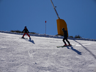 Skiers practicing their sport on the descent of a ski slope in a resort on a sunny winter day....
