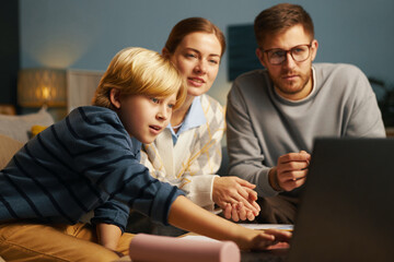 Multiracial family gathered on couch, watching movie on laptop, family interaction, bonding, and quality time being spent together in comfortable living room setting