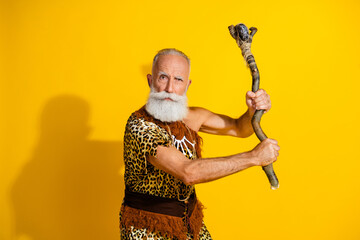Photo of ancient aged caveman hold stone ax wear leopard skin clothes isolated on yellow color background