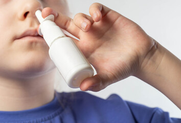 A caucasian girl sprays a spray into her nose to treat allergic rhinitis. Treatment of runny nose and nasal congestion with medical sprays, close-up