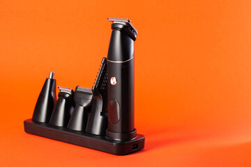 Modern set of hair trimmer with different attachments on a red background, close-up. Copy space for...