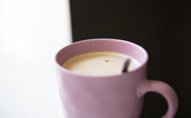 Close up of a pastel pink cup with hot coffee drink on white table 
