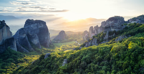 Amazing panoramic view of the Meteora valley with the monasteries in the golden hour of the sunset against the background of the setting sun, near Kastraki, Greece.