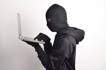Mysterious man wearing black hoodie and mask doing computer hacking activity, stealing personal information, isolated on white background.