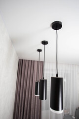 Modern black diode pendant lamps on a white stretch ceiling, designer, close-up