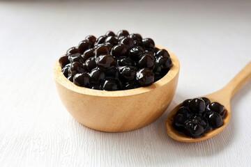 Black pearls for bubble mllk tea in a wooden bowl on white background