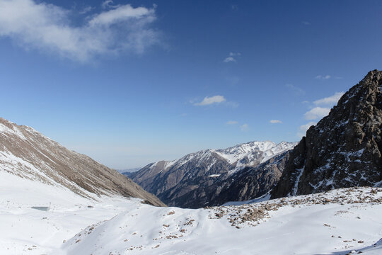 Snow-covered mountain peaks rising above a quiet winter valley under a bright blue sky