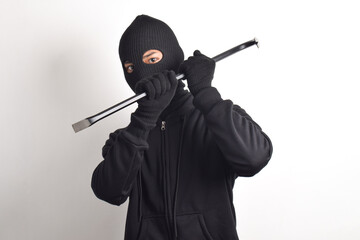 Thief wearing black jacket and mask holding crowbar, isolated on white background.