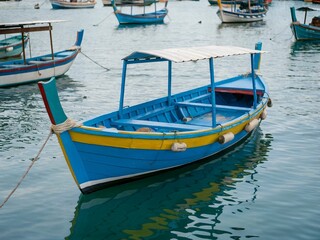 Obraz premium Luzzu - Traditional Maltese Wooden Boat Docked in Quiet Coastal Marina, Malta