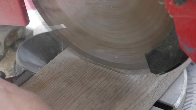 A carpenter meticulously cuts timber to size outdoors using a powerful table saw