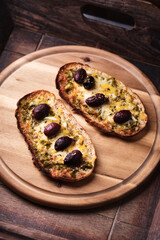 Bruschetta with mozzarella and cheddar cheese, olive pesto and kalamata olives. on wooden background. Soft focus. Close up
