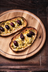 Bruschetta with mozzarella and cheddar cheese, olive pesto and kalamata olives. on wooden background. Soft focus. Close up