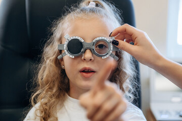 Portrait, in glasses, looking forward. Little girl at the ophthalmologist clinic with doctor