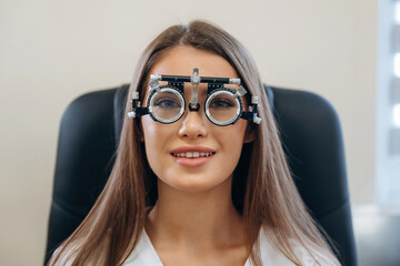 Positive facial expression. Young woman is checking her vision in the ophthalmologist cabinet