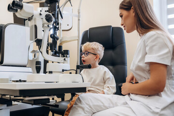 In the glasses. Little boy is having check up in the ophthalmologist cabinet